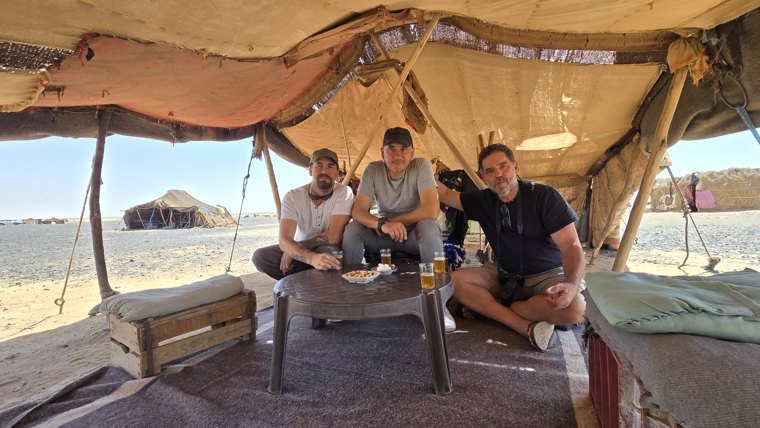 Tea in the desert. The three Changos sharing bread and tea in a nomad tent in the Moroccan Sahara, invited by a Berber woman. A simple, authentic stop worth more than many miles on the road.